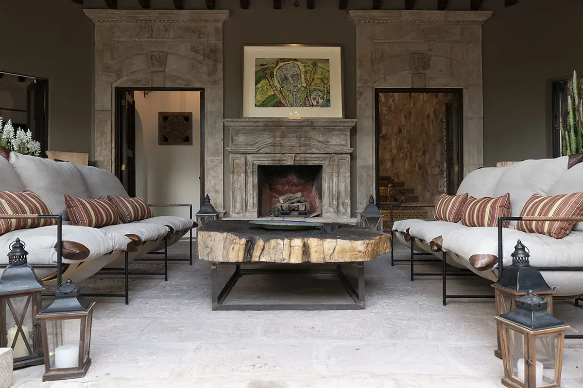 Casa Nola, loggia lounge with a stone fireplace and white cushioned sofas, San Miguel de Allende