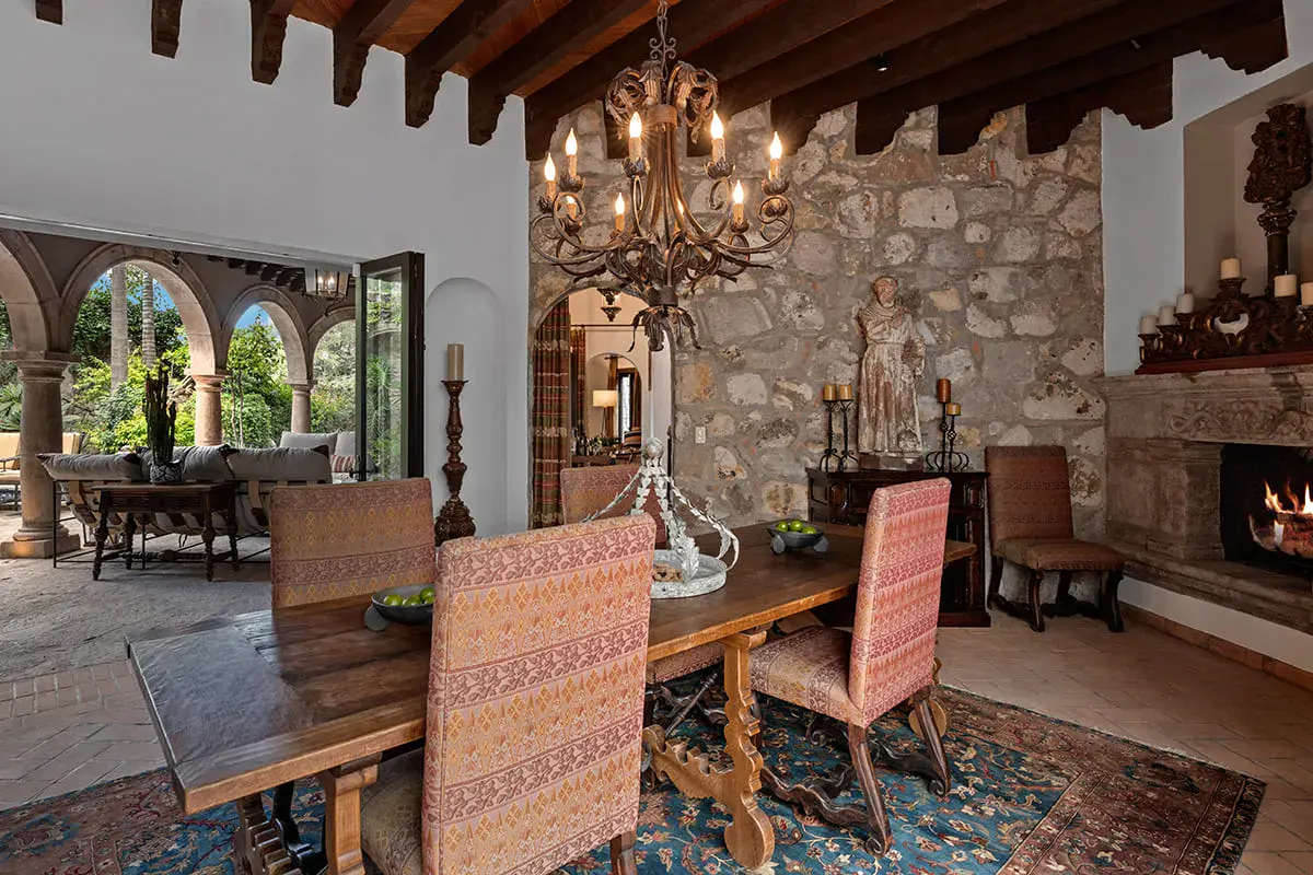 Casa Nola, dining room with a wood table, a chandelier and a stone wall, San Miguel de Allende