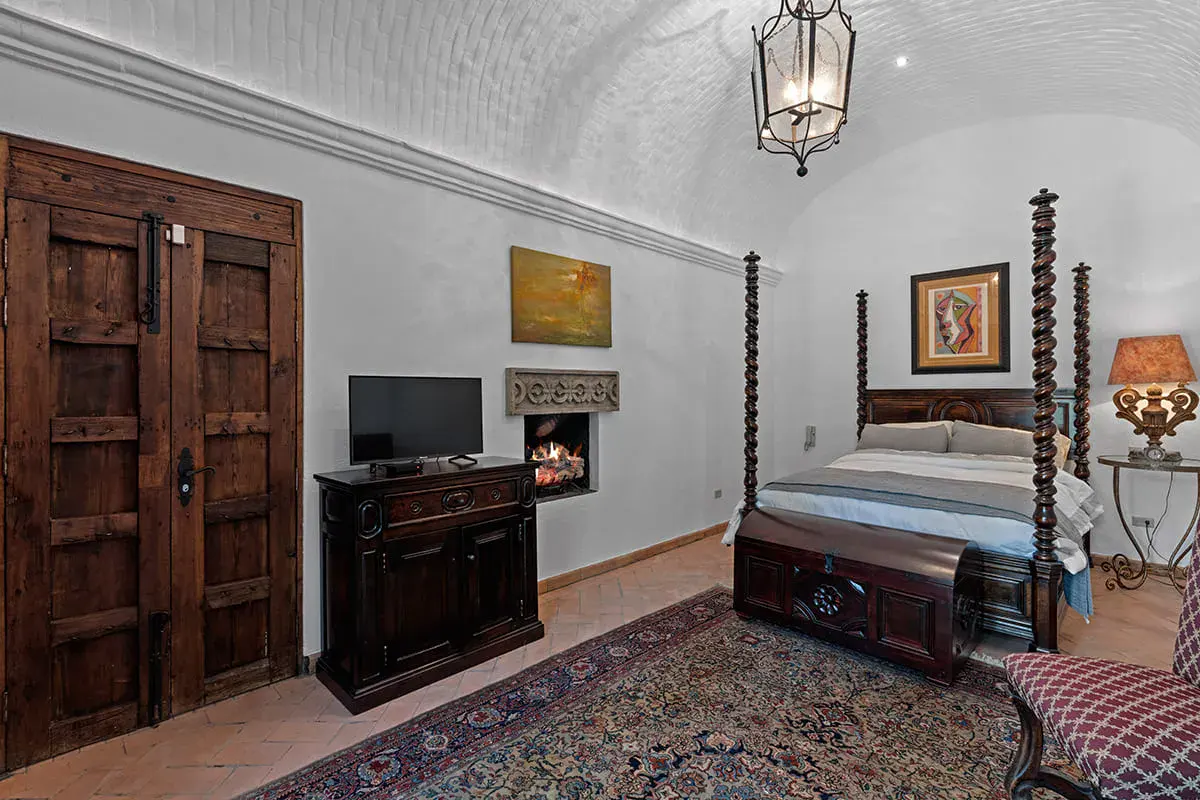 Casa Nola, bedroom with a carved four-poster bed and a vaulted ceiling, San Miguel de Allende