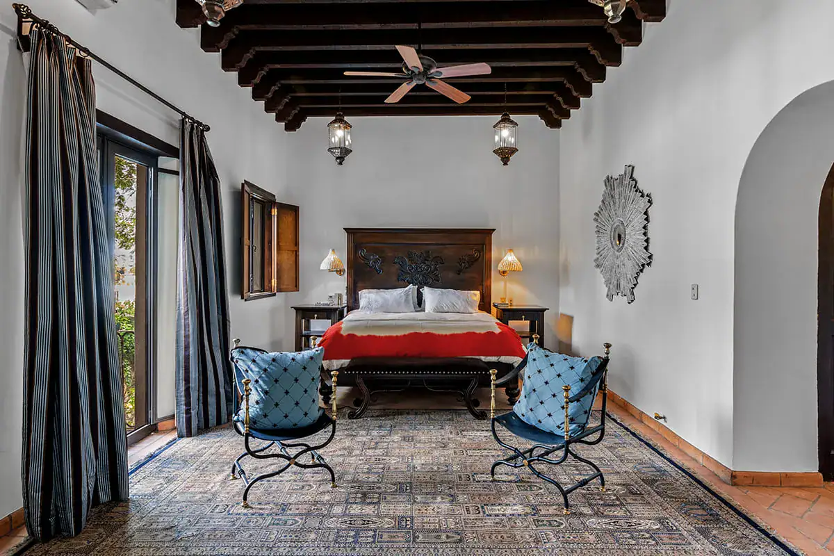 Casa Nola, bedroom with a red bedspread, a wrought-iron balcony and blue chairs, San Miguel de Allende