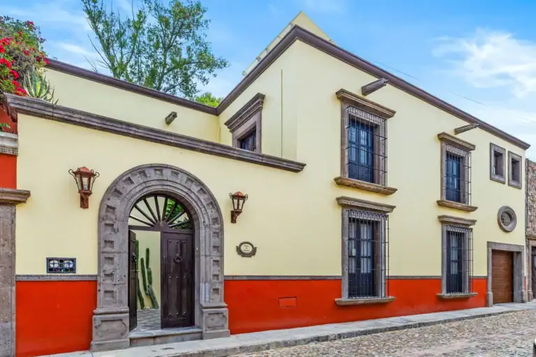 Casa Nostra Familia, yellow and red stucco facade with a stone arched doorway on a cobblestone street, San Miguel de Allende
