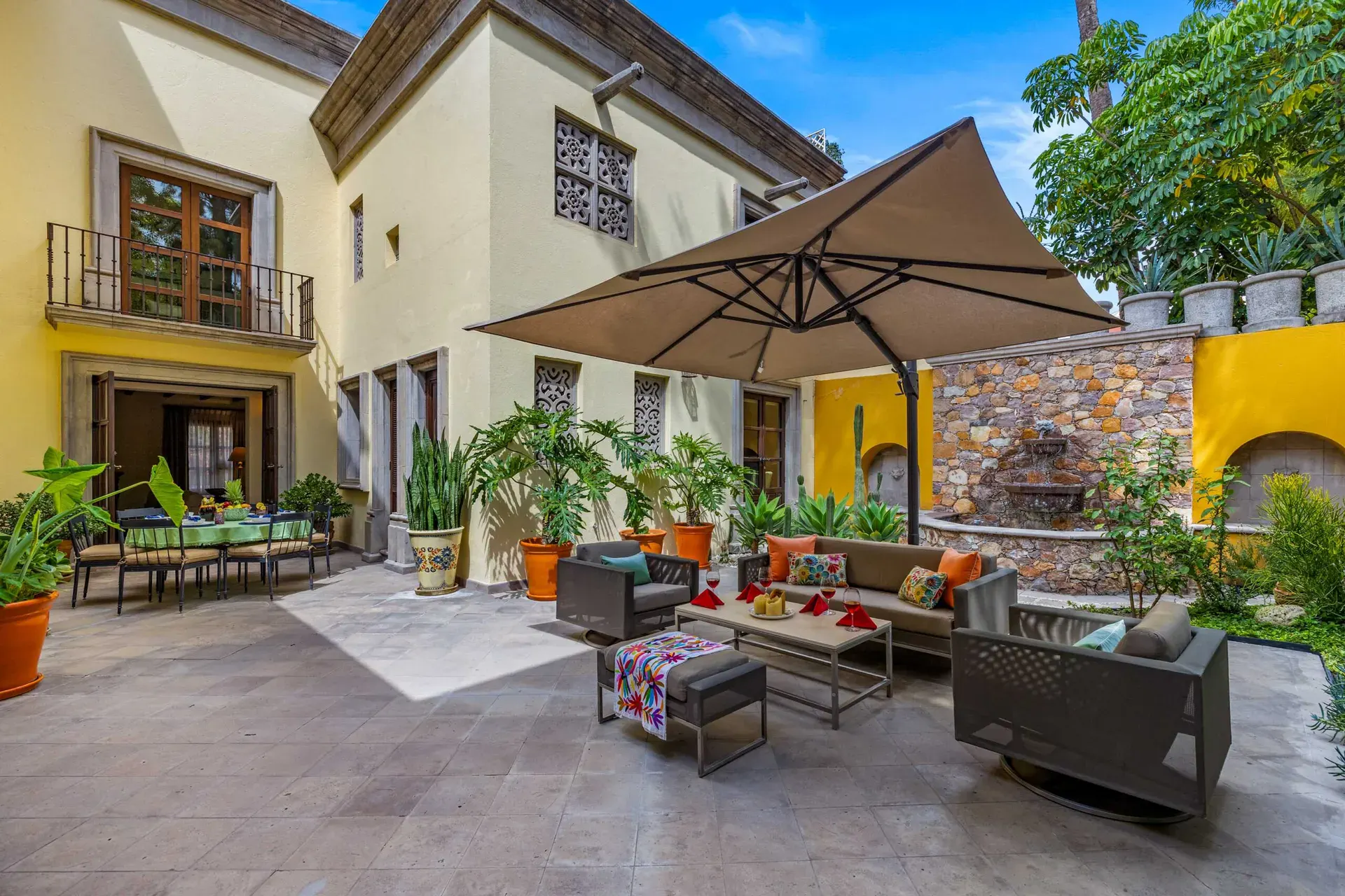 Casa Nostra Familia, courtyard patio with an umbrella, outdoor sofas and a stone wall fountain, San Miguel de Allende