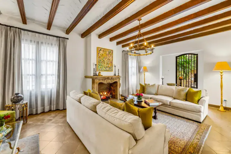 Casa Nostra Familia, living room with a stone fireplace, cream sofas and a beamed ceiling, San Miguel de Allende
