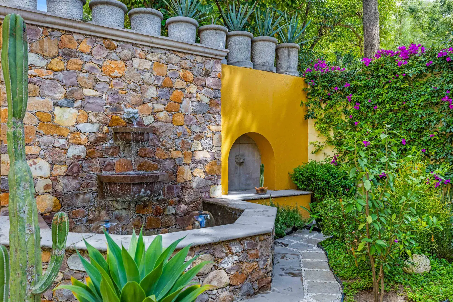 Casa Nostra Familia, stone wall fountain beside a yellow wall and bougainvillea, San Miguel de Allende