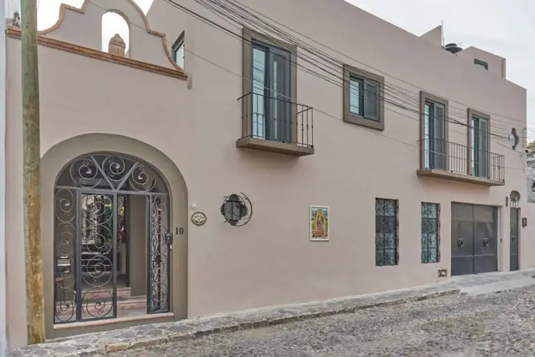 Casa Oasis, street facade with an arched wrought-iron gate and balcony windows, San Miguel de Allende