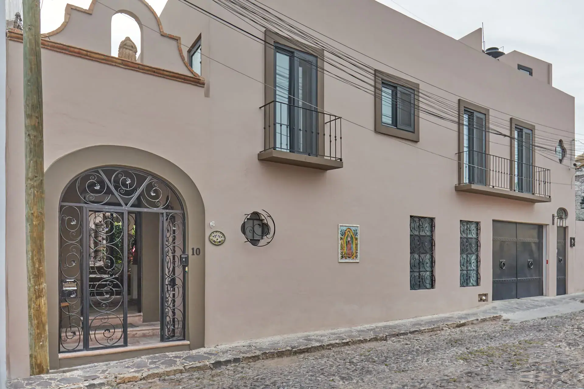 Casa Oasis, street facade with an arched wrought-iron gate and balcony windows, San Miguel de Allende