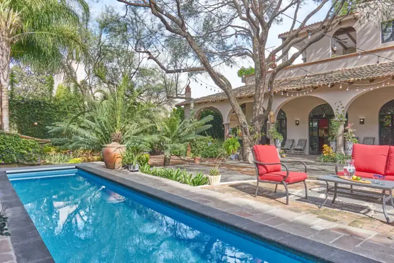 Casa Oasis, lap pool with red lounge chairs among palms and gardens, San Miguel de Allende