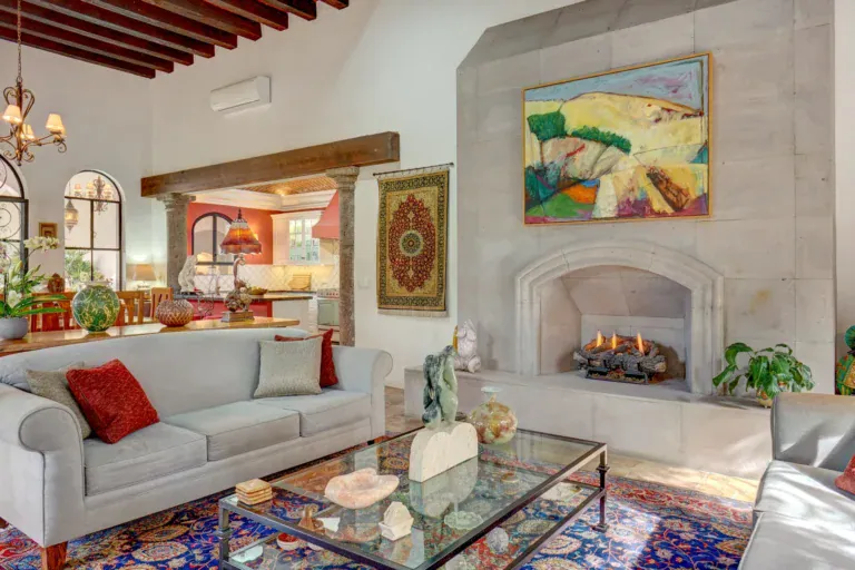 Casa Oasis, living room with a fireplace, gray sofa and a colorful rug, San Miguel de Allende