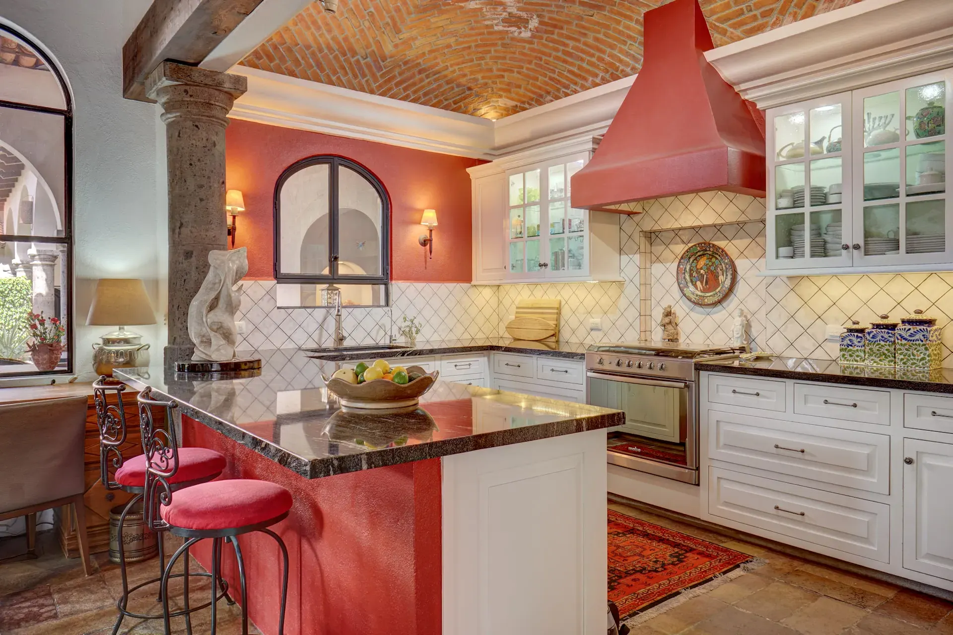 Casa Oasis, kitchen with a granite island, red stools and a red hood, San Miguel de Allende