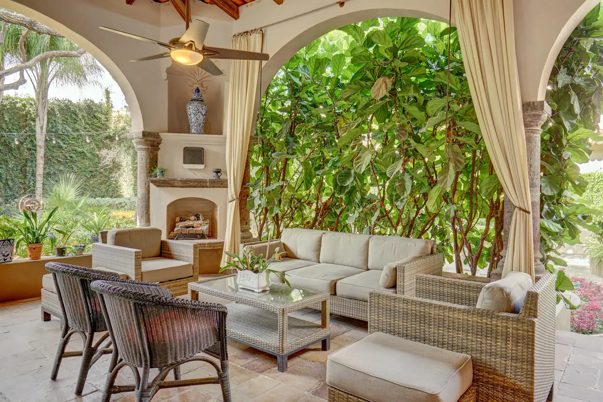 Casa Oasis, covered garden lounge with wicker sofas and a corner fireplace, San Miguel de Allende