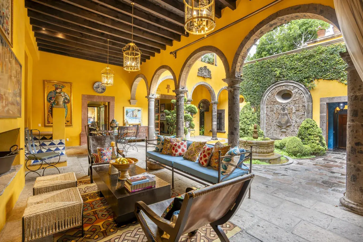 Casa Obelisco, arcaded courtyard lounge with blue cushions under a beamed ceiling, San Miguel de Allende