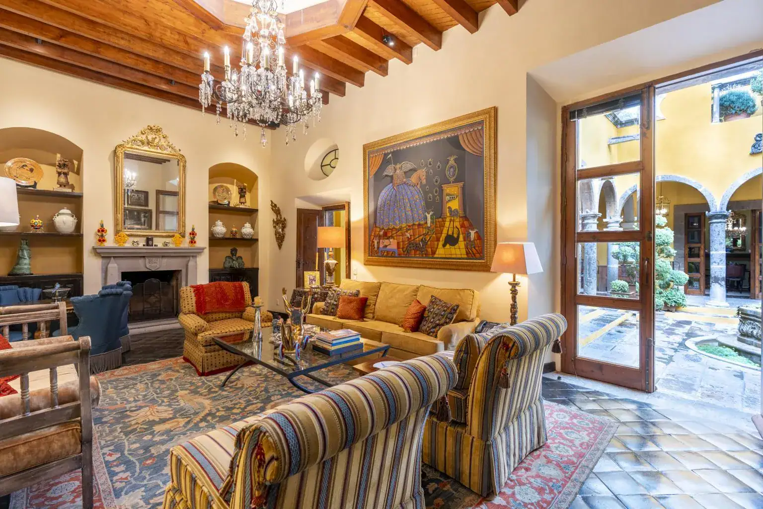 Casa Obelisco, living room with a fireplace, striped sofas and a crystal chandelier, San Miguel de Allende