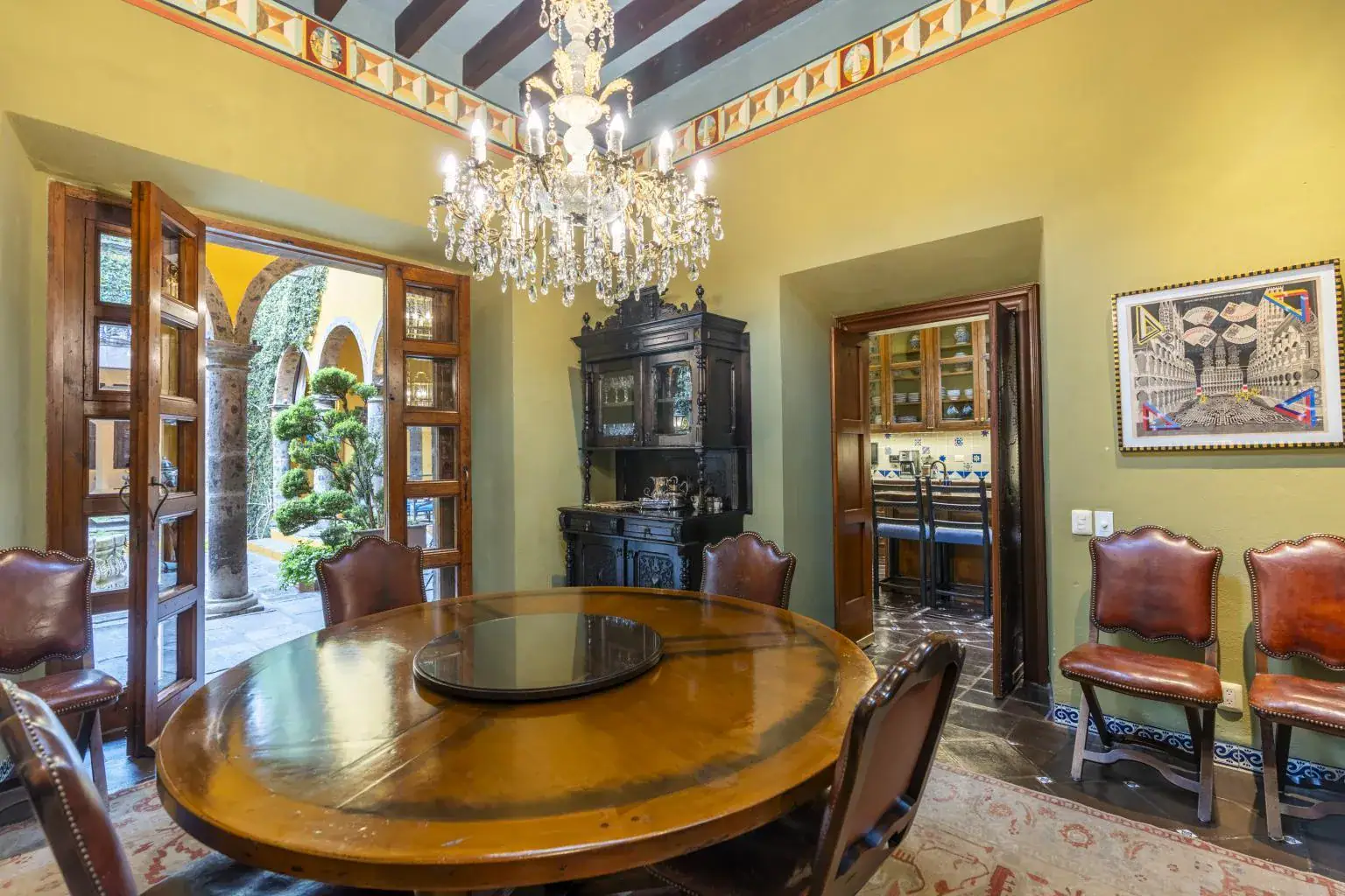 Casa Obelisco, dining room with a round wood table and a chandelier, San Miguel de Allende