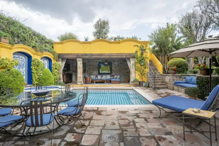Casa Obelisco, courtyard pool with blue tile, lounge chairs and an outdoor dining table, San Miguel de Allende