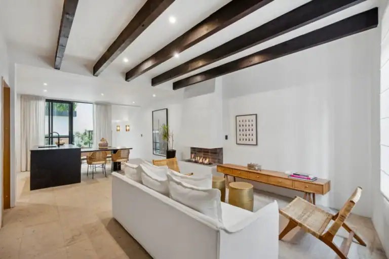 Casa Palma, living area with a white sofa, wicker chairs, a fireplace and the kitchen island beyond, San Miguel de Allende