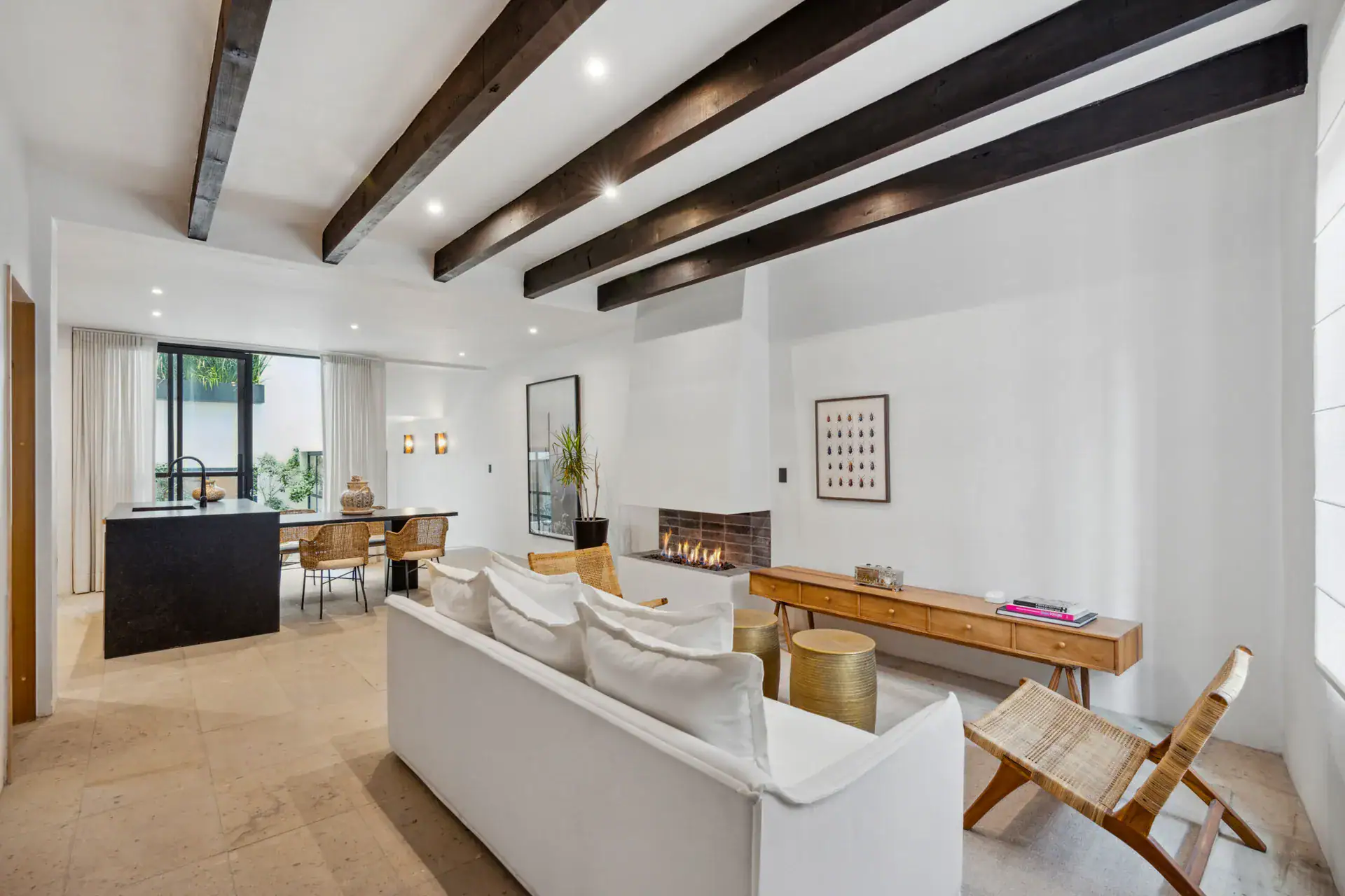 Casa Palma, living area with a white sofa, wicker chairs, a fireplace and the kitchen island beyond, San Miguel de Allende