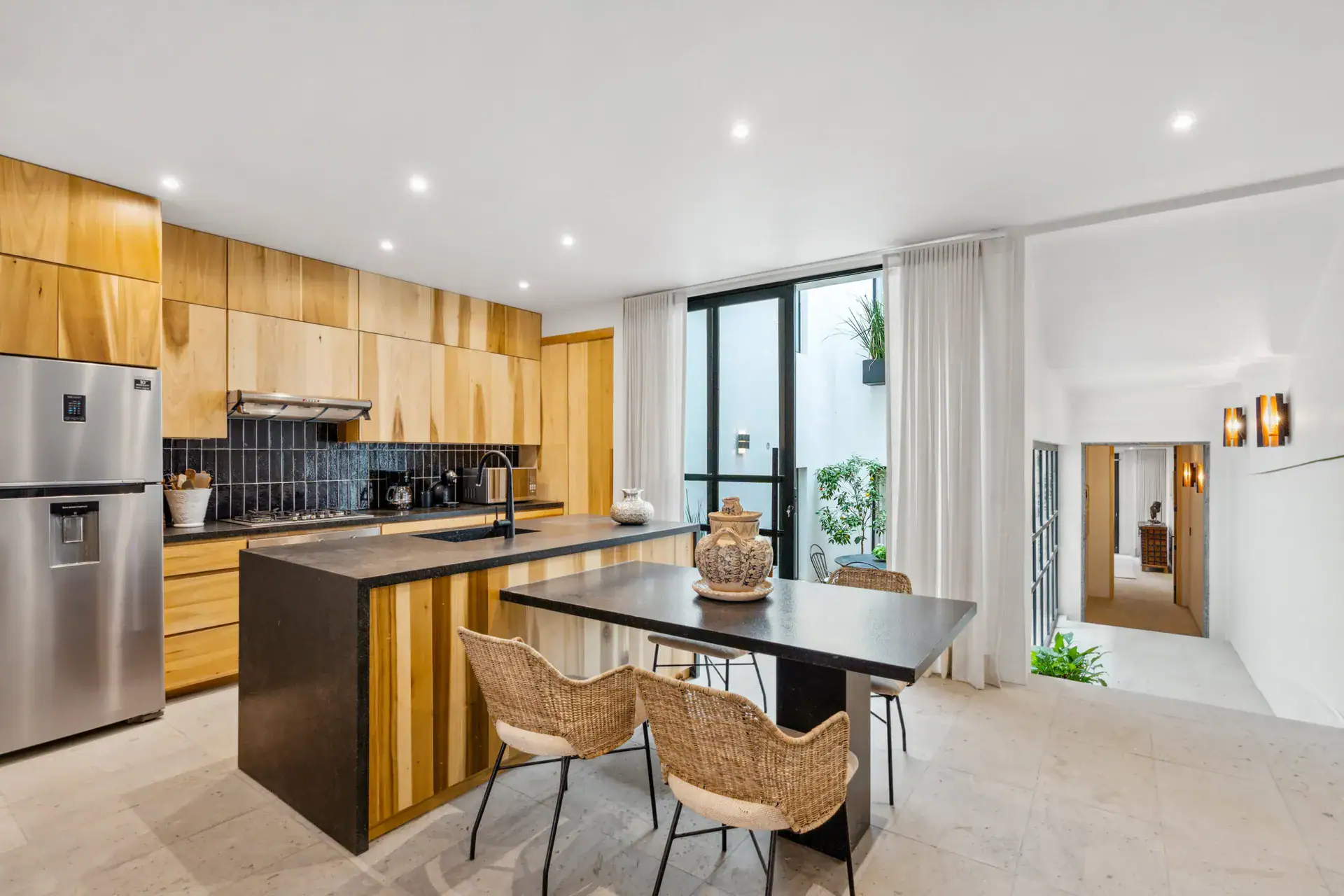 Casa Palma, kitchen with a stainless refrigerator, a black counter island and wicker dining chairs, San Miguel de Allende