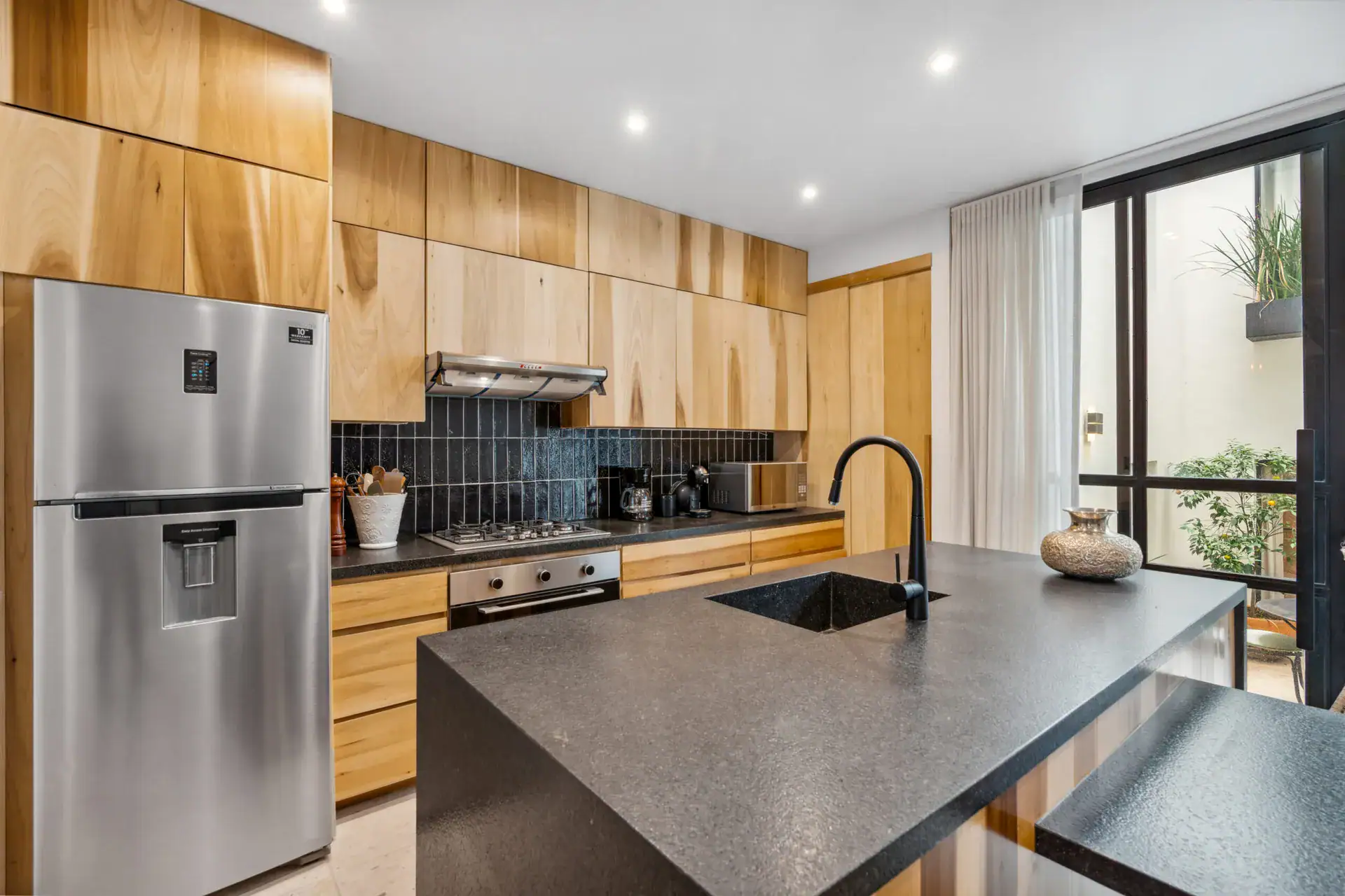 Casa Palma, kitchen with wood cabinets, a black backsplash and a sink with a black faucet, San Miguel de Allende