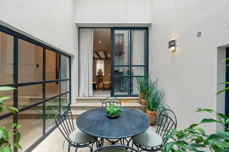 Casa Palma, courtyard dining set outside a steel-framed glass wall with the interior beyond, San Miguel de Allende