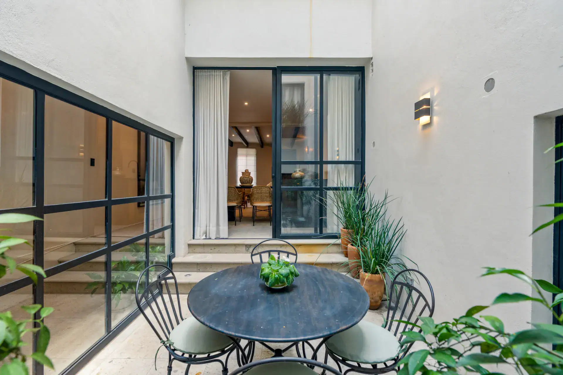 Casa Palma, courtyard dining set outside a steel-framed glass wall with the interior beyond, San Miguel de Allende