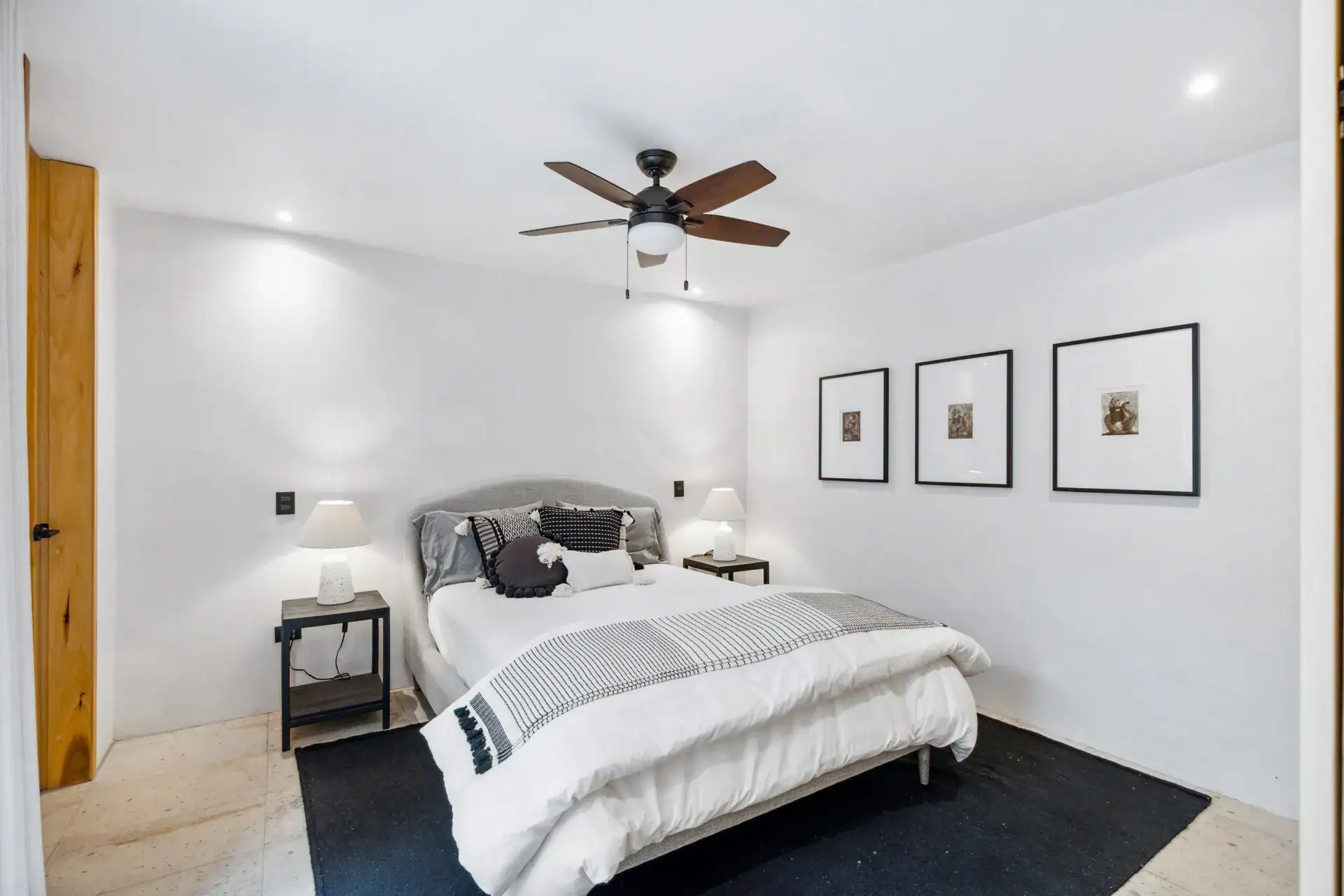 Casa Palma, bedroom with a gray headboard, white bedding, a black rug and three framed prints, San Miguel de Allende
