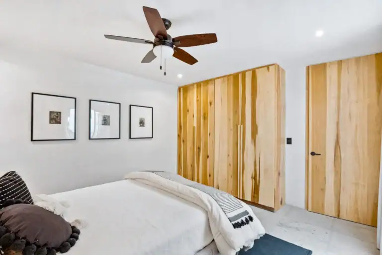 Casa Palma, bedroom with a ceiling fan, framed prints and a wall of natural wood closets, San Miguel de Allende