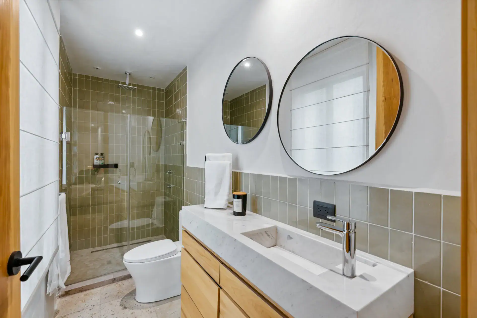 Casa Palma, bathroom with a double round mirror, an olive tile shower and a wood vanity, San Miguel de Allende