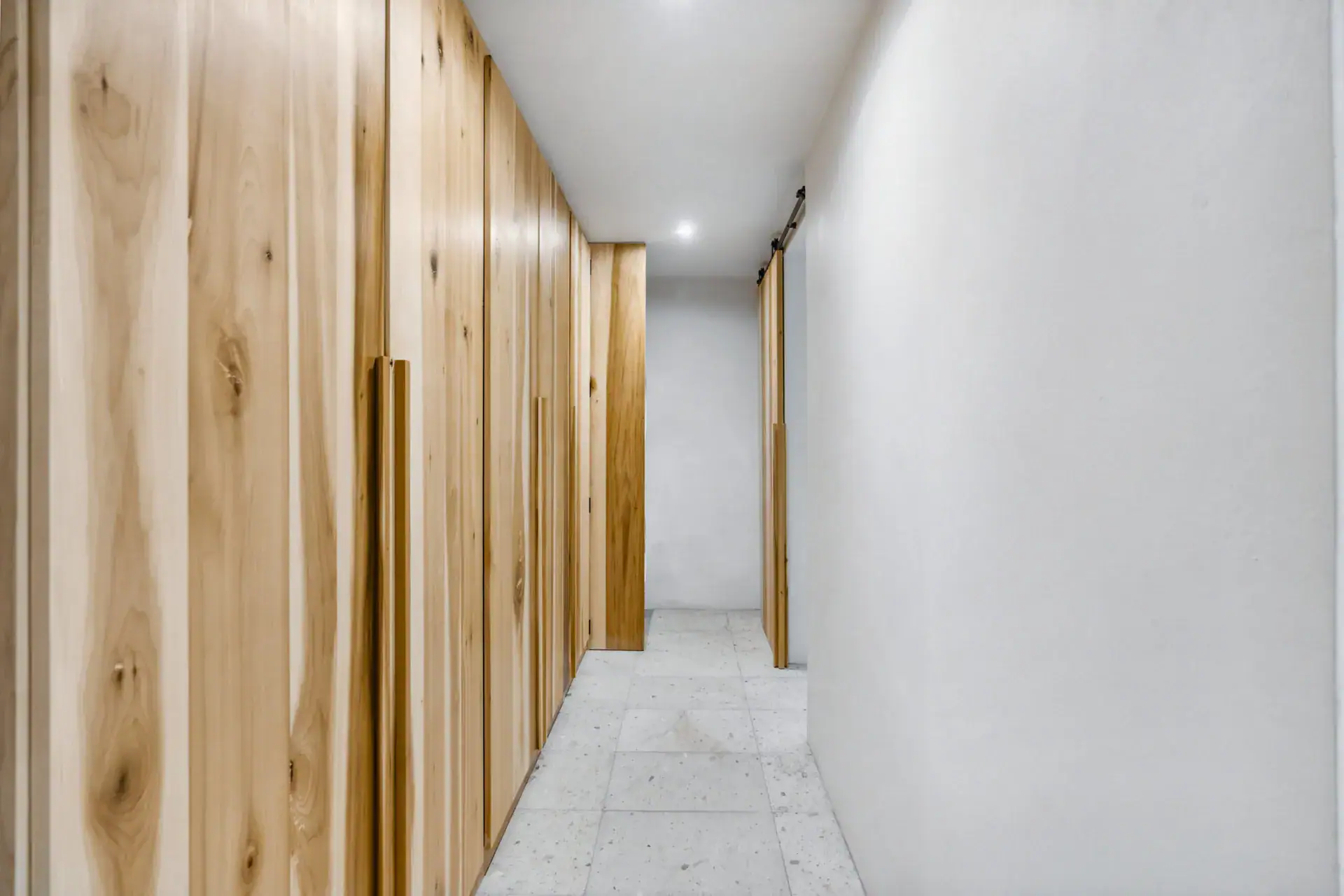 Casa Palma, hallway lined with wood closet doors and a sliding barn door, San Miguel de Allende