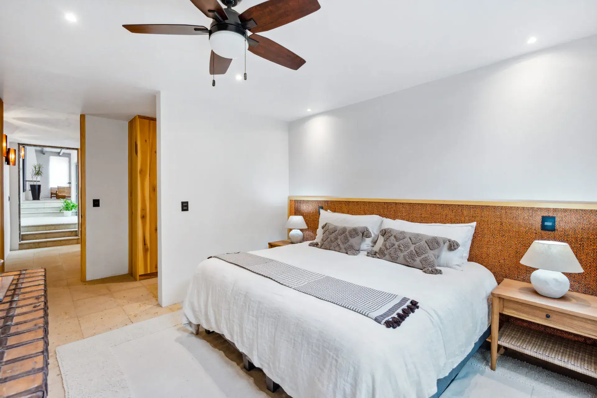 Casa Palma, bedroom with a woven headboard, a table lamp and a view to the hallway, San Miguel de Allende