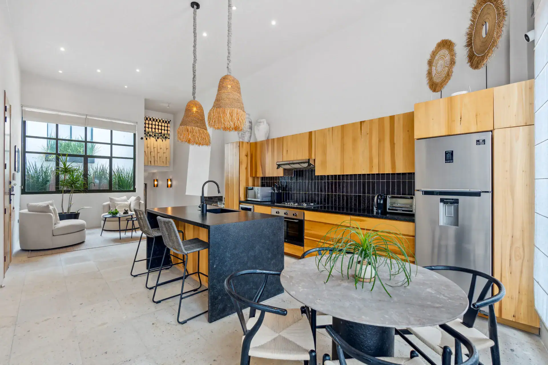 Casa Palma, kitchen and living area with woven pendant lights, a wood wall and a stainless refrigerator, San Miguel de Allende