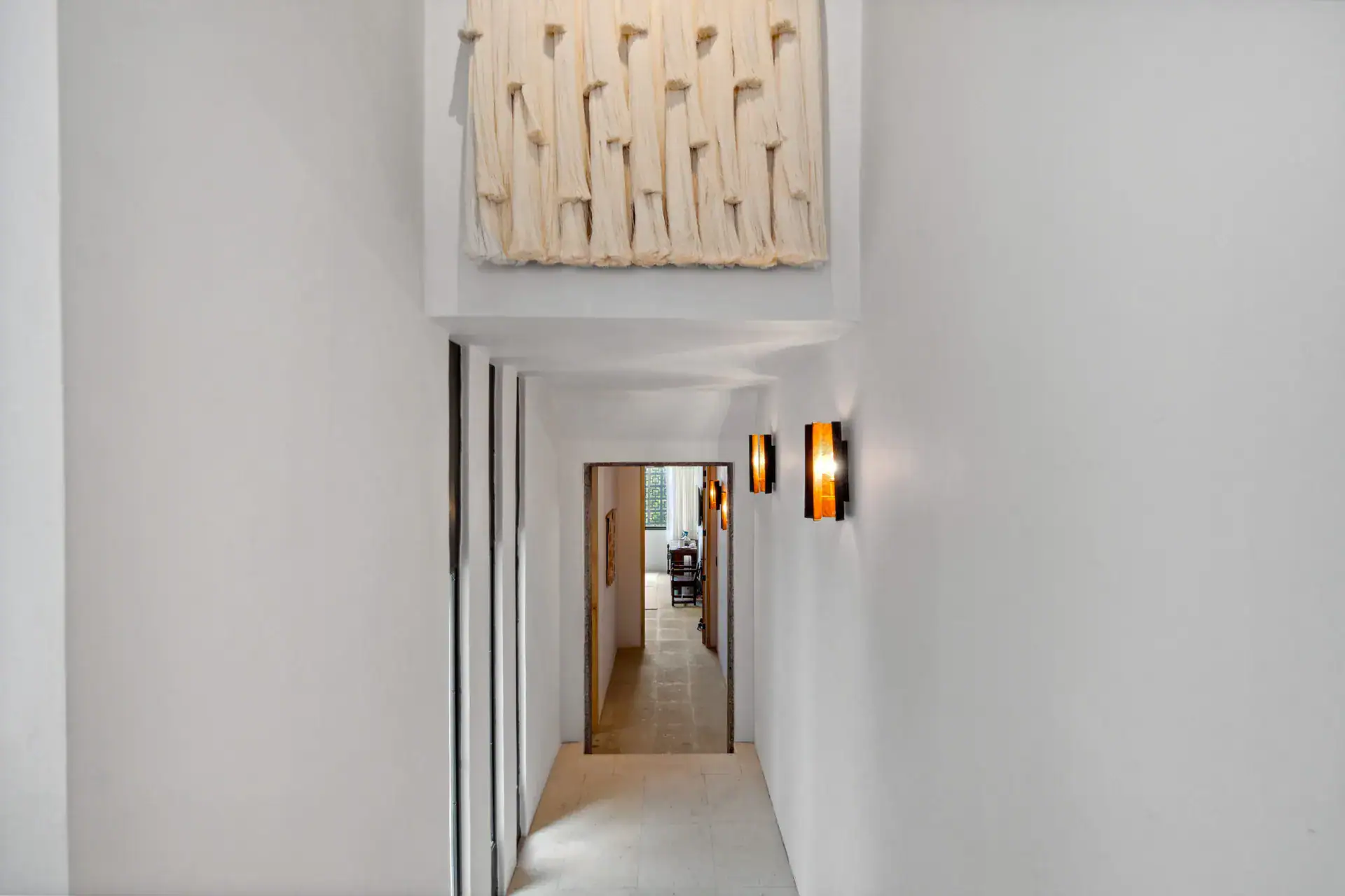 Casa Palma, upstairs hallway with a woven textile wall hanging and sconces, San Miguel de Allende