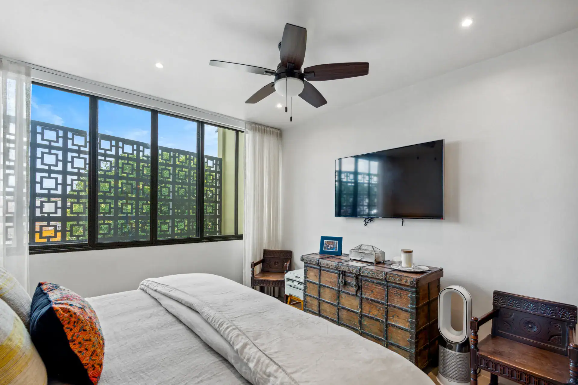 Casa Palma, bedroom with a patterned screen window, a wall-mounted television and an antique chest, San Miguel de Allende
