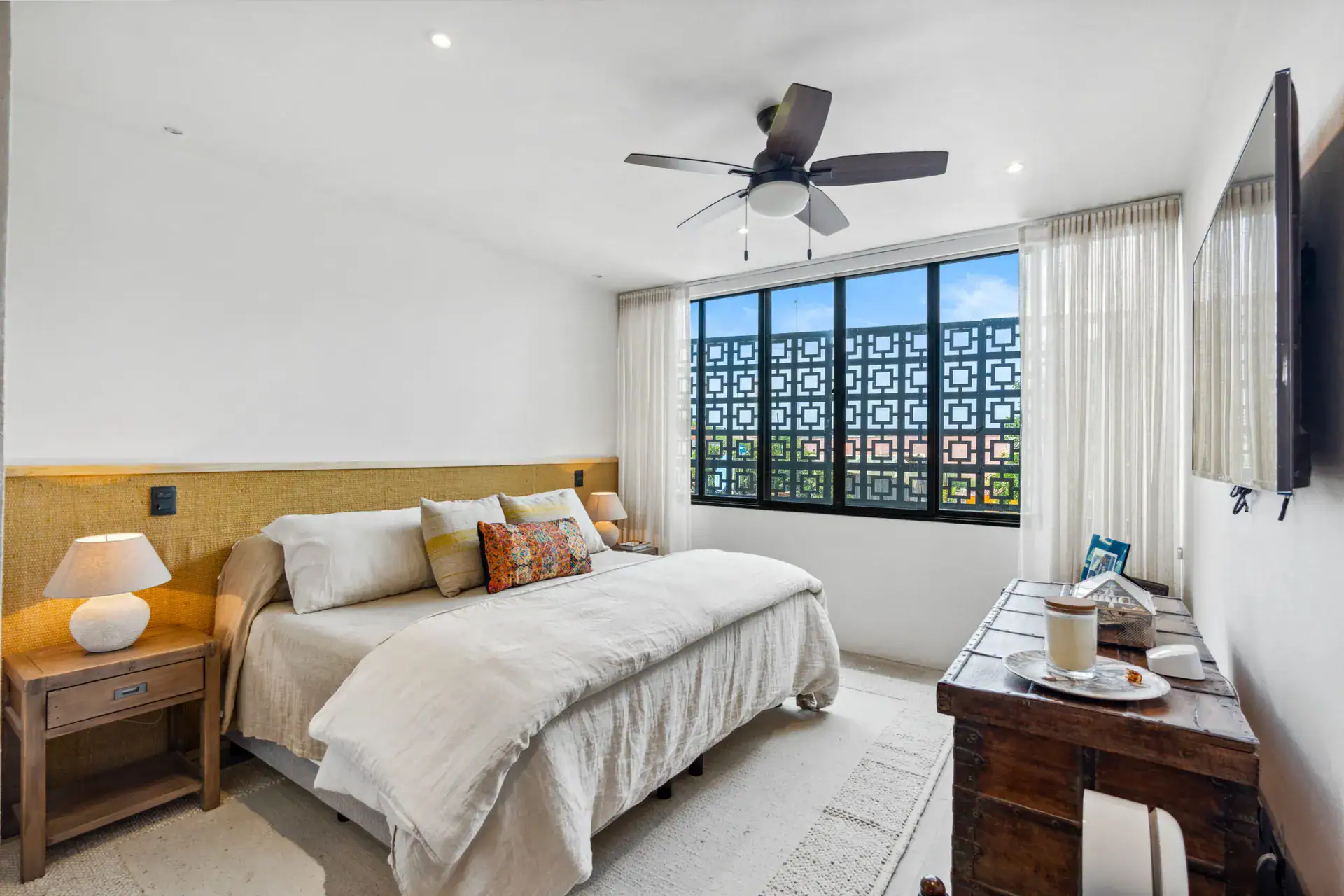 Casa Palma, bedroom with a woven headboard, orange patterned pillows and an antique chest, San Miguel de Allende