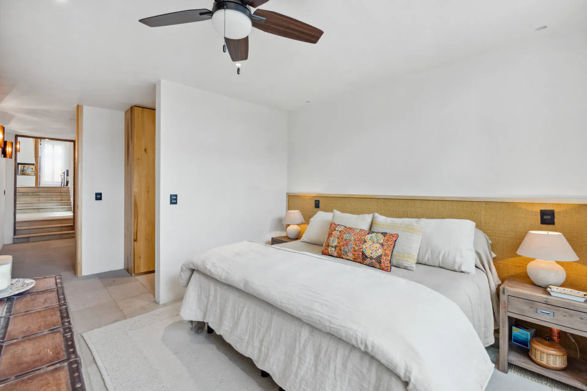 Casa Palma, bedroom seen from the hallway with a woven headboard and white bedding, San Miguel de Allende