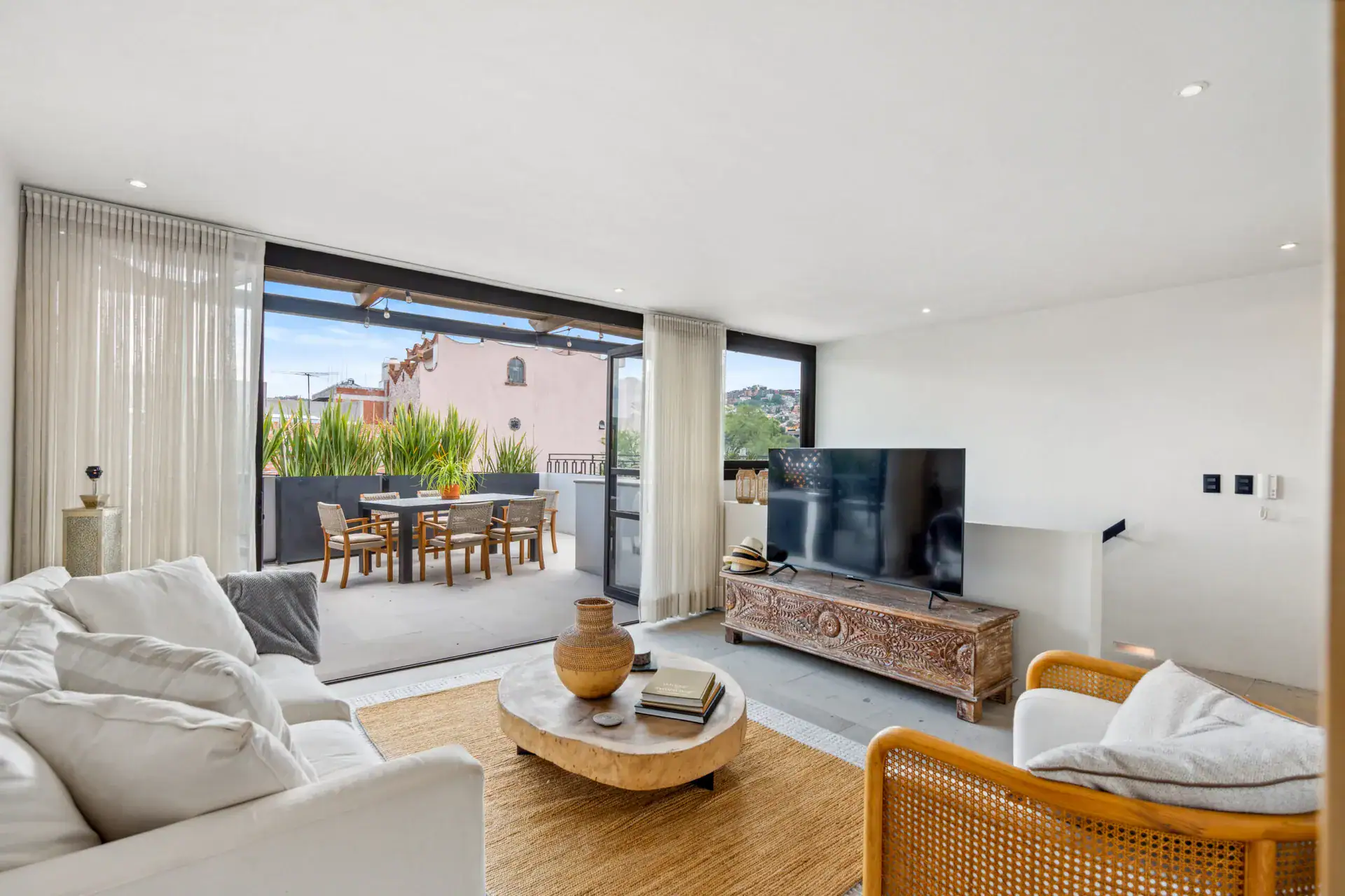 Casa Palma, living room with a television, a carved wood console and a terrace beyond, San Miguel de Allende