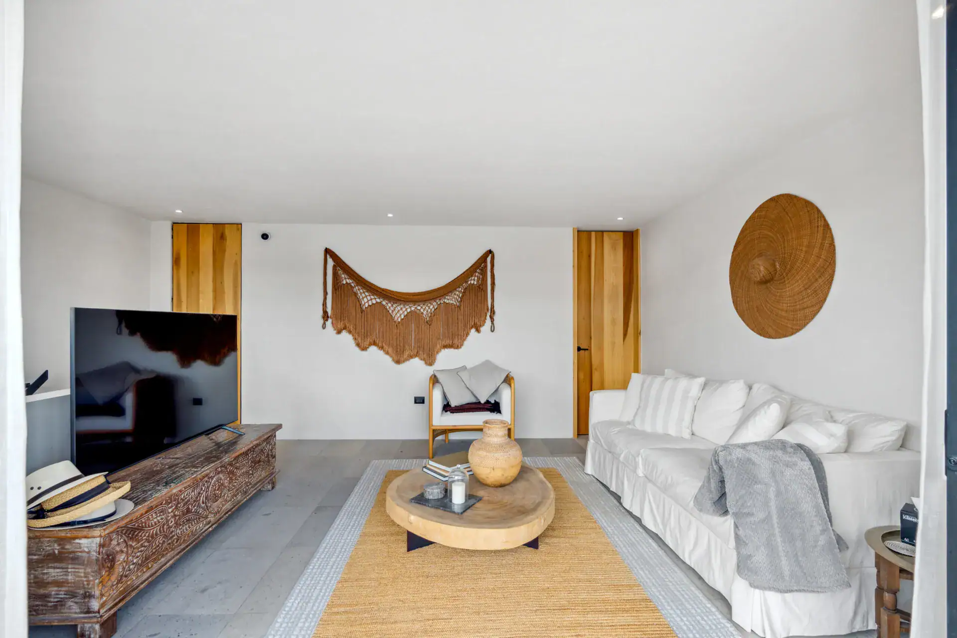 Casa Palma, living room with a white sofa, a carved wood console, a woven wall hanging and a woven hat decoration, San Miguel de Allende