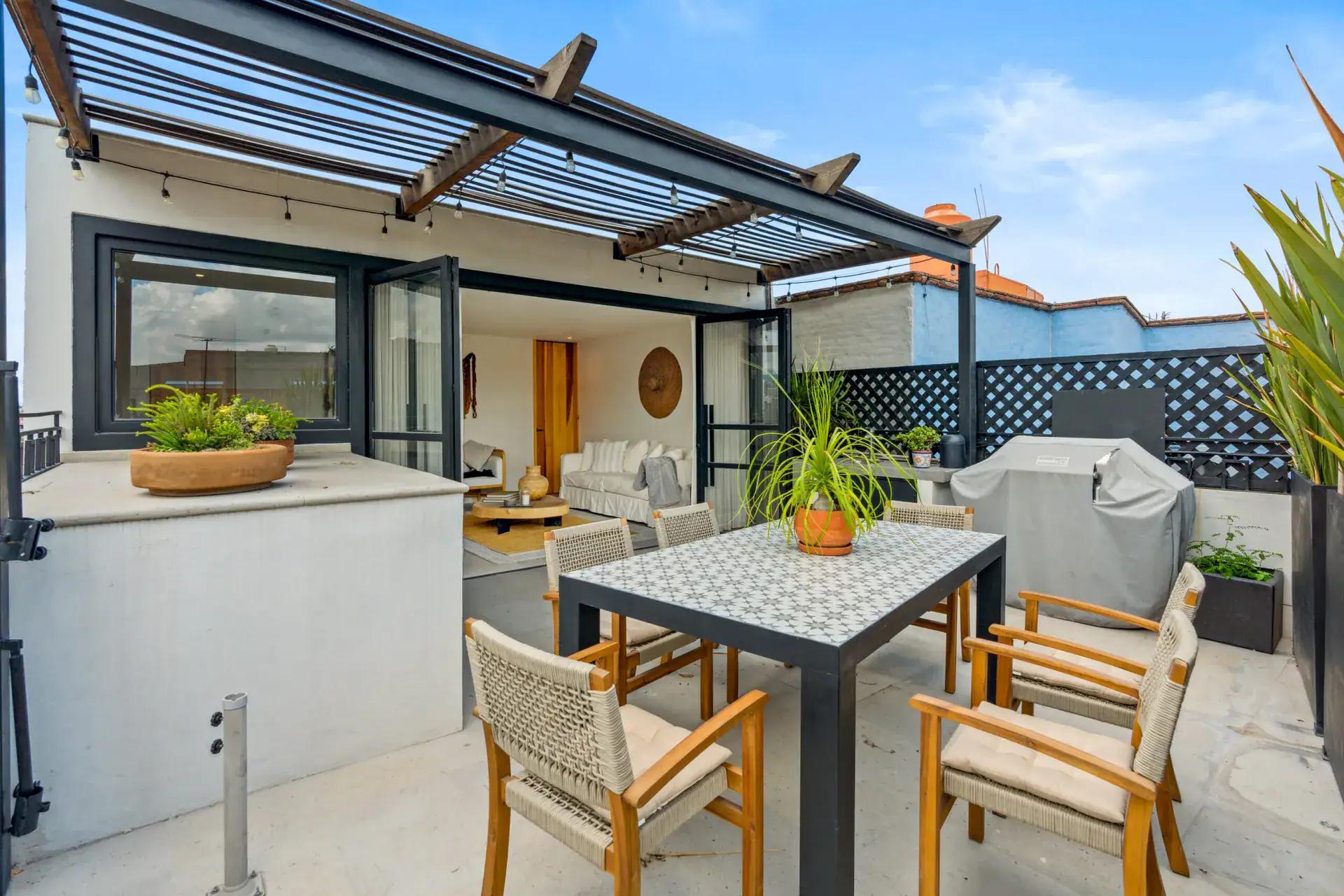 Casa Palma, rooftop terrace with a pergola, a dining table and a barbecue, with the living room beyond, San Miguel de Allende