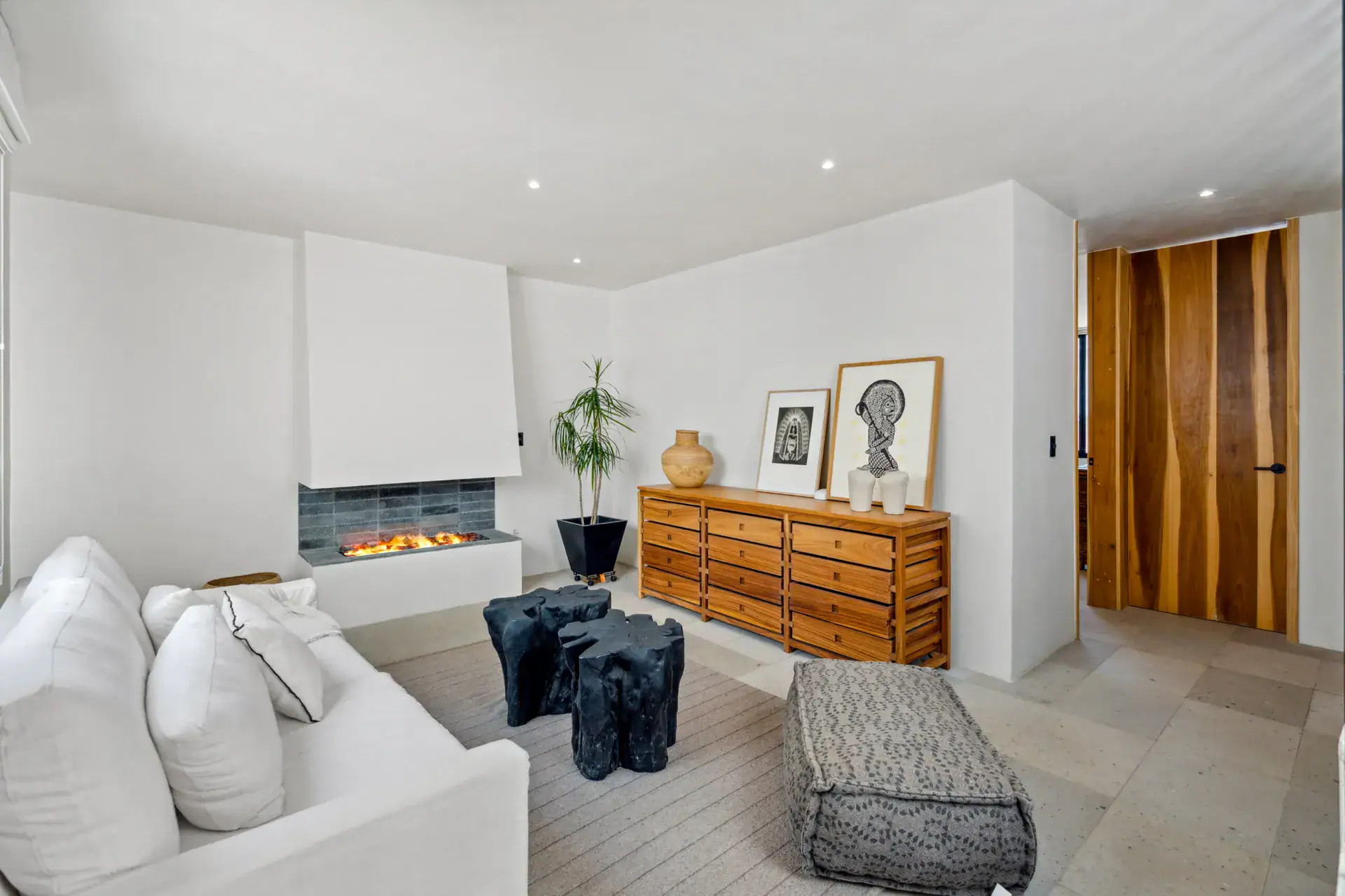 Casa Palma, living room with a corner fireplace, a white sofa and a wood chest of drawers, San Miguel de Allende