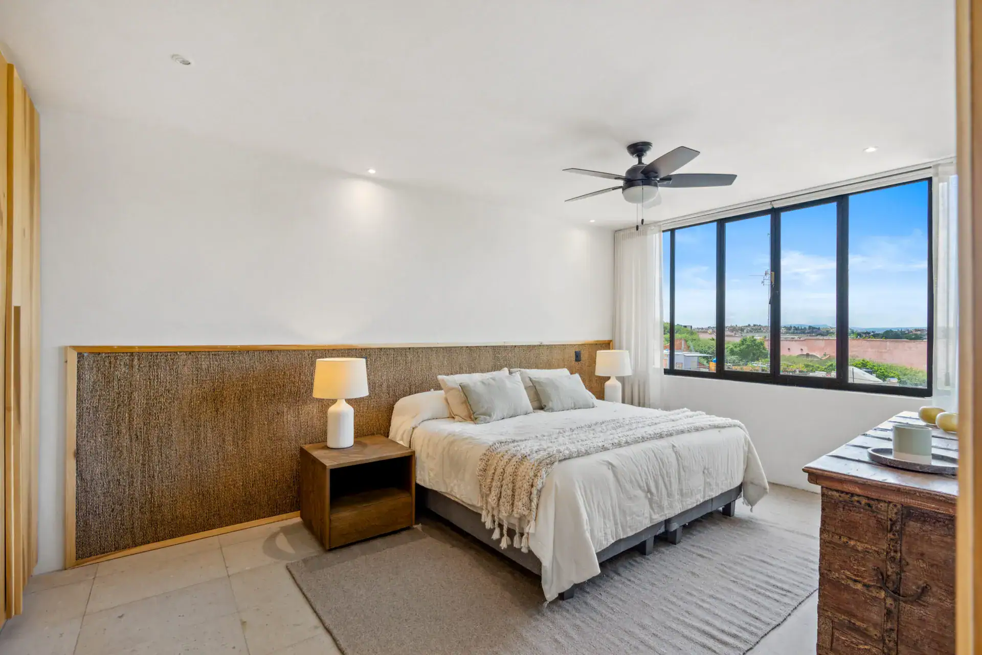 Casa Palma, bedroom with a woven headboard, a landscape view window and a wood chest, San Miguel de Allende