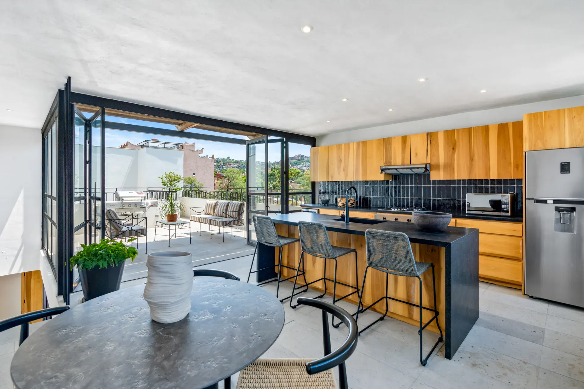 Casa Palma, upper kitchen opening through folding glass doors to the rooftop terrace, San Miguel de Allende