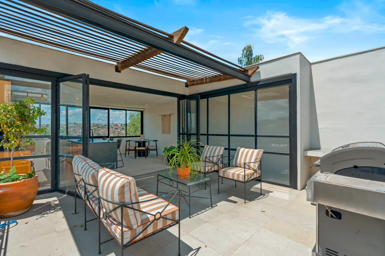 Casa Palma, rooftop lounge with striped chairs, a grill and a pergola with folding glass doors, San Miguel de Allende