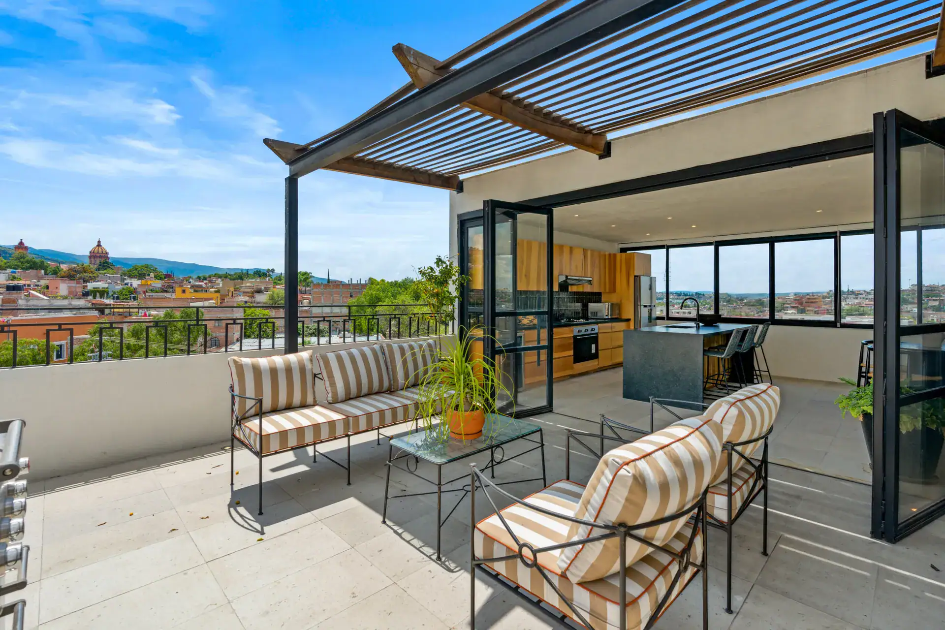 Casa Palma, rooftop terrace with a striped sofa set, a pergola and views of the Parroquia and hills, San Miguel de Allende