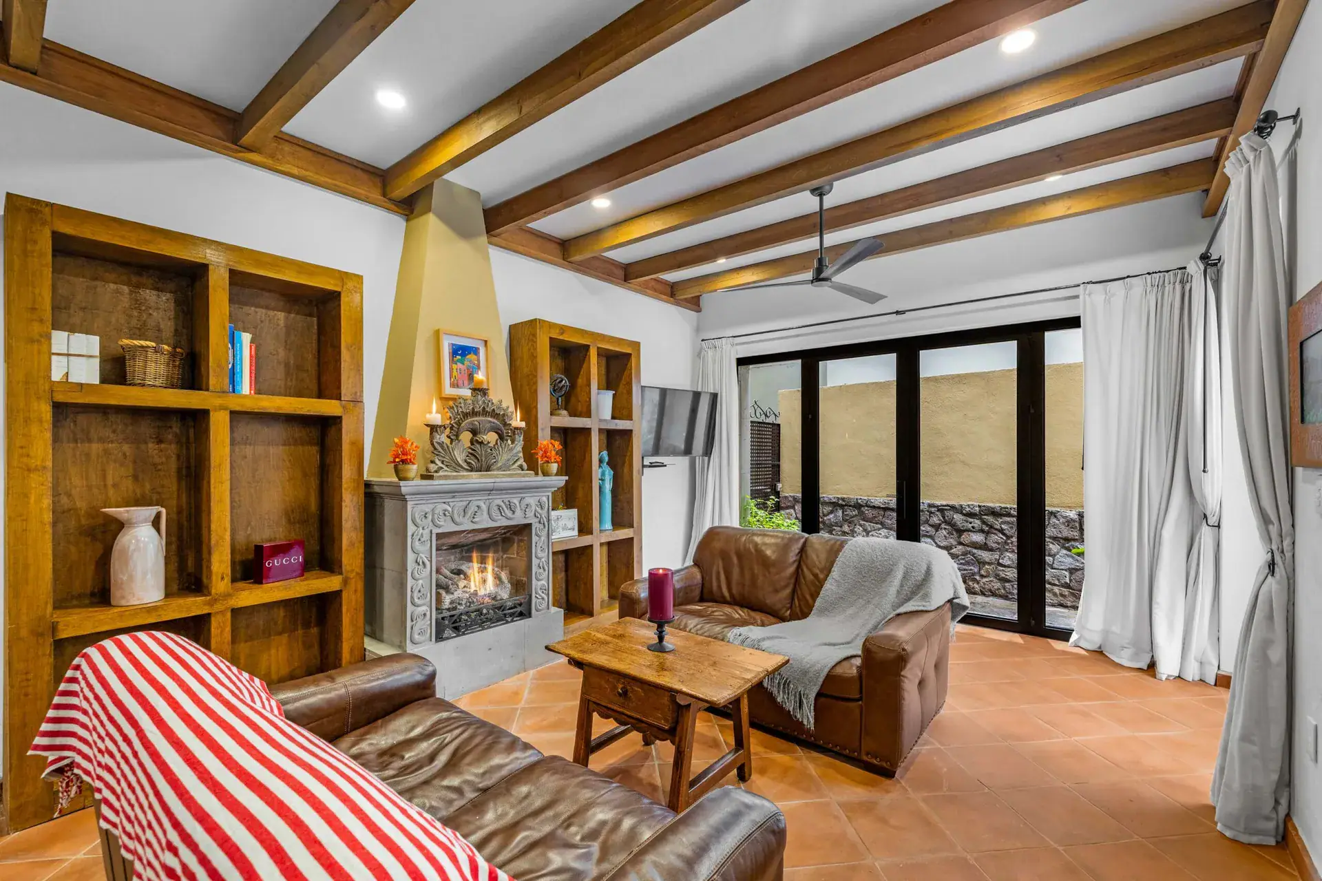 Casa Paradise, living room with built-in wood shelves and a stone fireplace, San Miguel de Allende