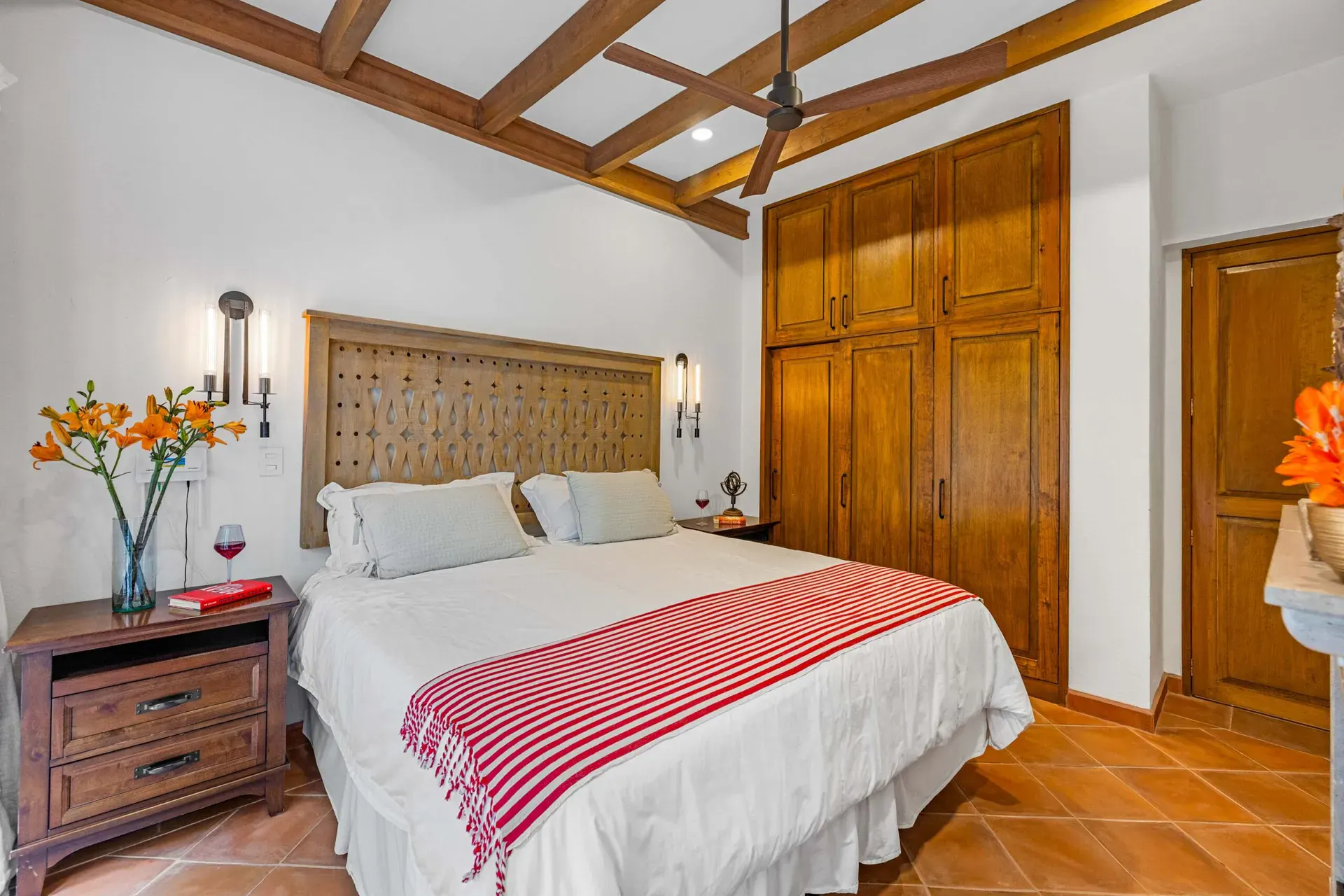 Casa Paradise, bedroom with a carved wood headboard and a red striped blanket, San Miguel de Allende