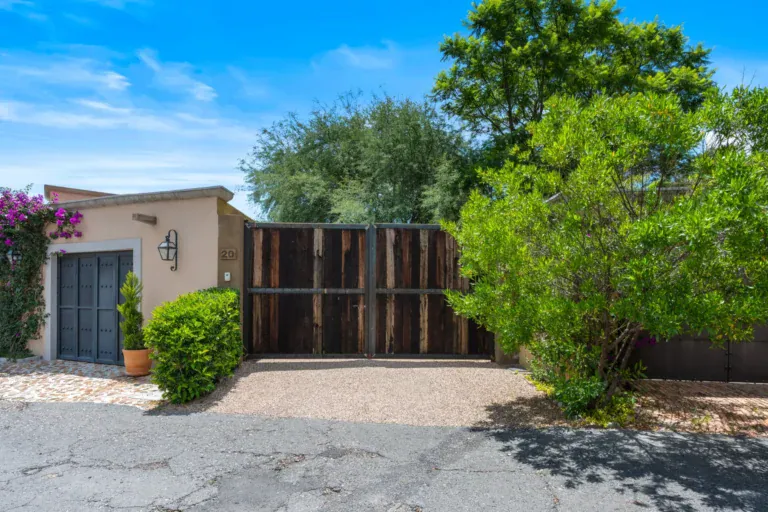 Casa Paz, walled entrance with a dark wood gate and a stucco house among olive trees, San Miguel de Allende