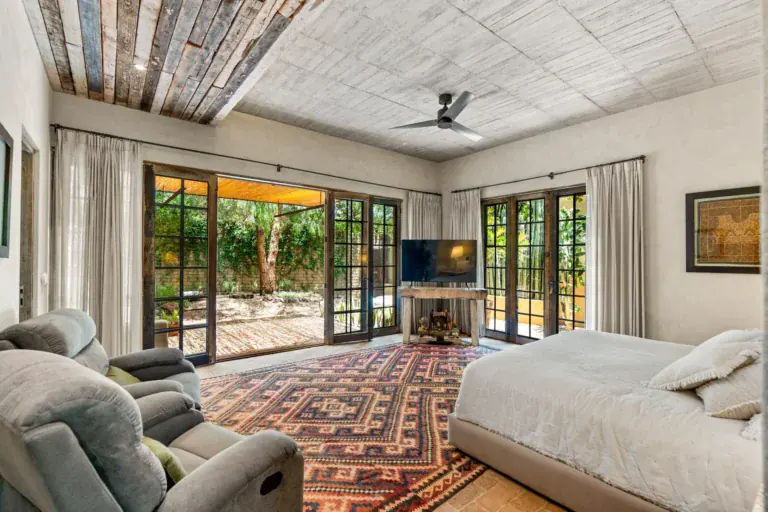 Casa Paz, primary bedroom with glass doors opening to the garden and a reclaimed wood ceiling, San Miguel de Allende