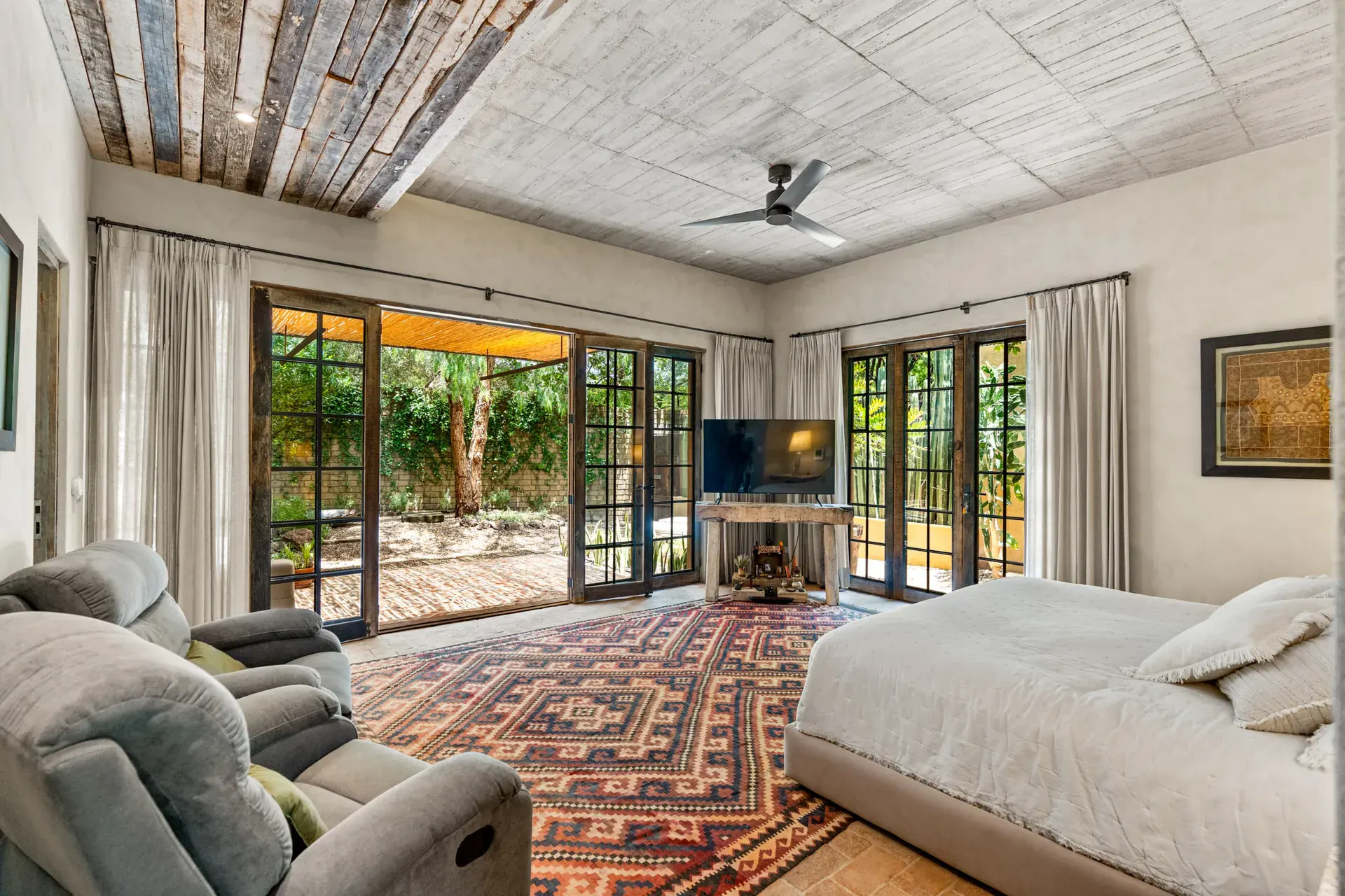 Casa Paz, primary bedroom with glass doors opening to the garden and a reclaimed wood ceiling, San Miguel de Allende