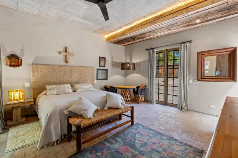 Casa Paz, bedroom with a woven headboard, a bench and a patterned rug, San Miguel de Allende