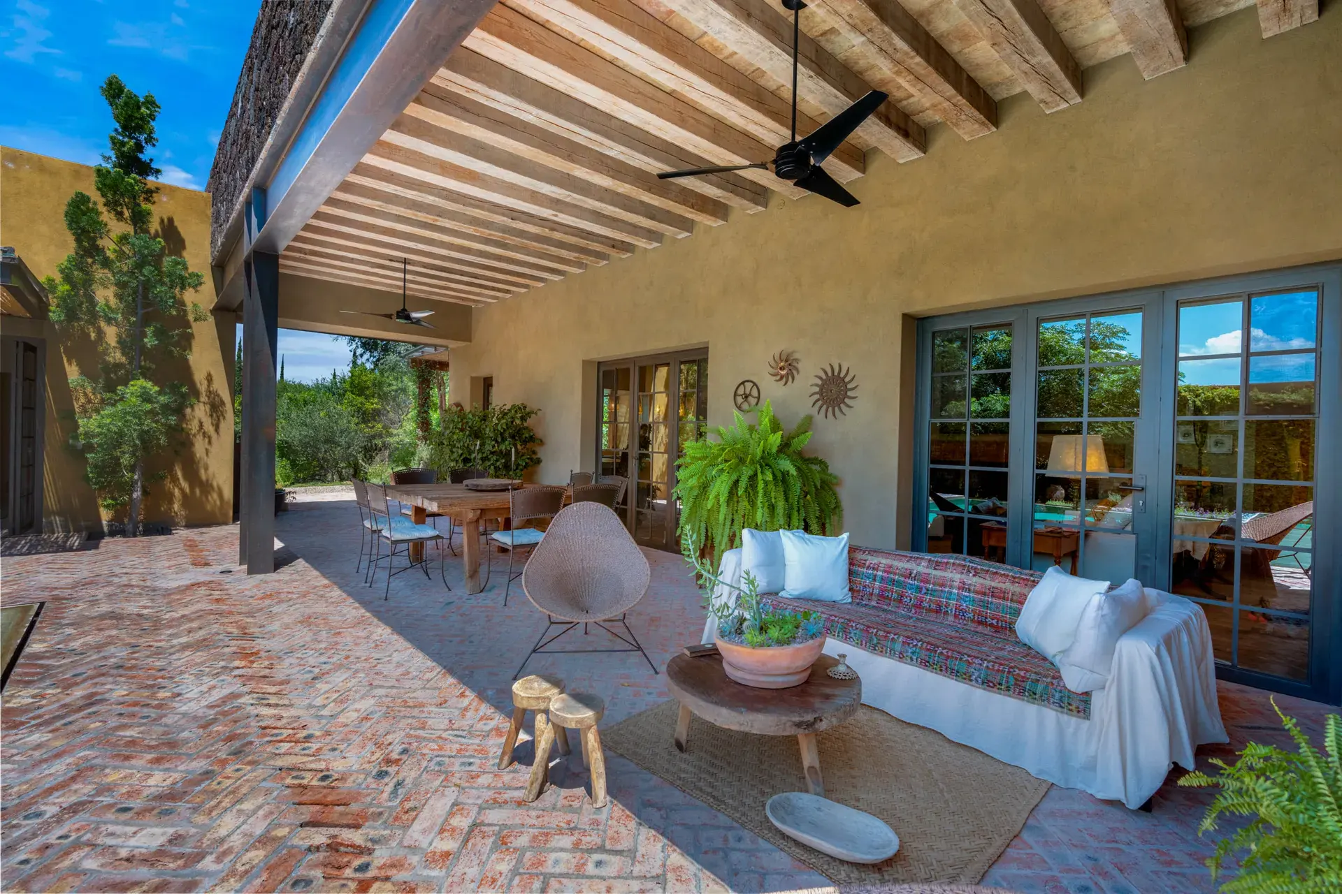 Casa Paz, covered terrace with a long sofa, a hammock chair and a brick floor, San Miguel de Allende