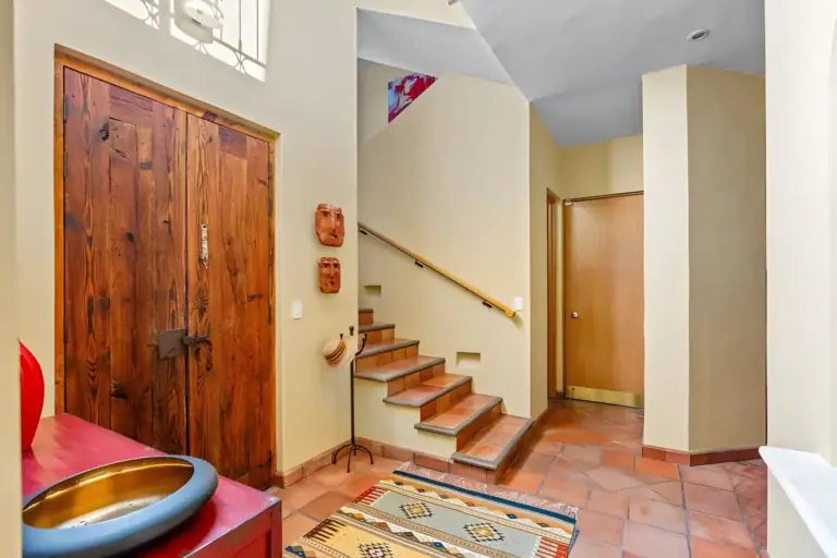 Casa Privada, entry hall with a carved double wooden door, terracotta floors and stairs to the upper level, San Miguel de Allende